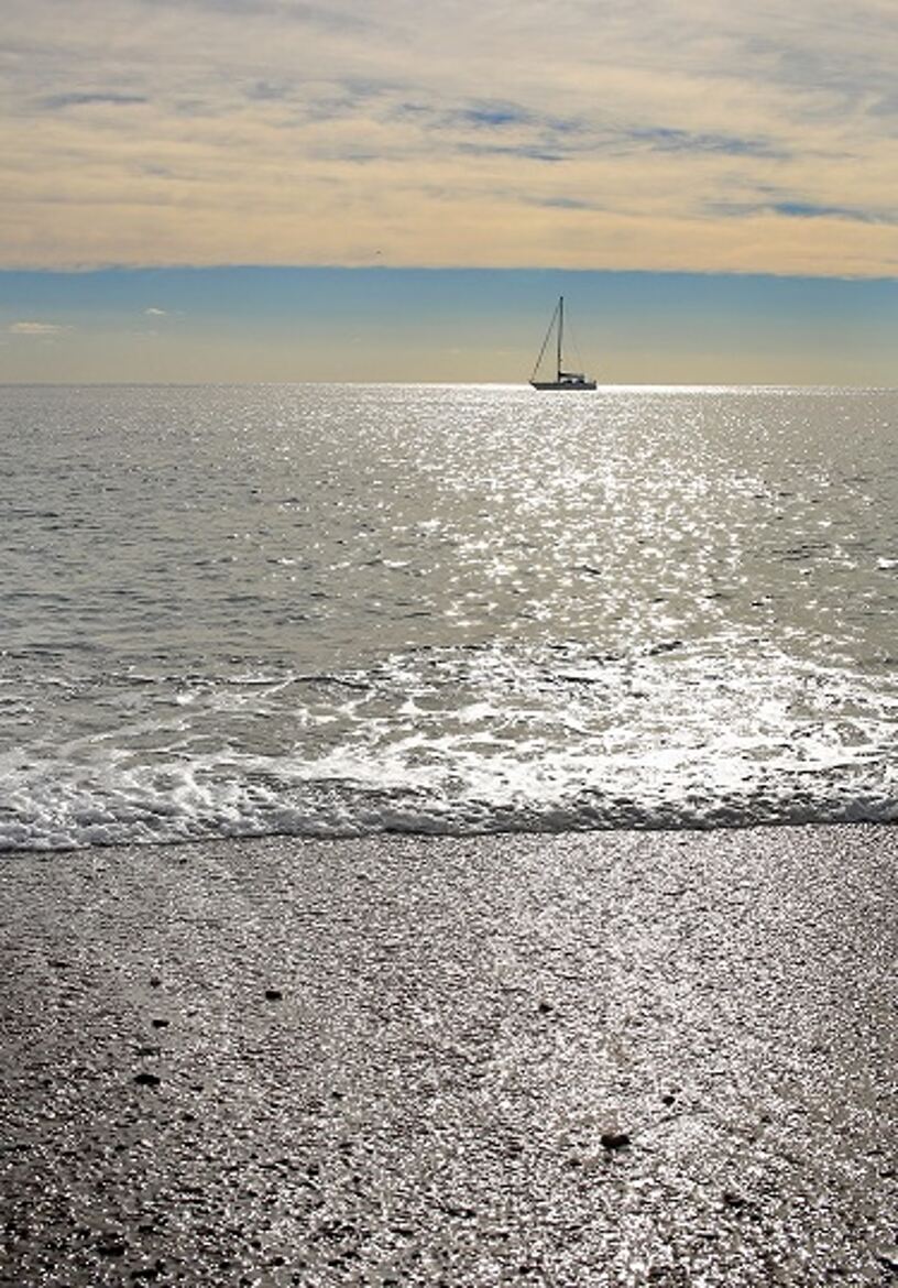 Un voilier passe dans la brise du matin.